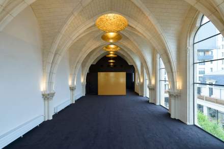 Couloir avec une moquette bleu et des lustres dorés dans l'hôtel séminaire Hôtel de la Paix au centre ville de Reims